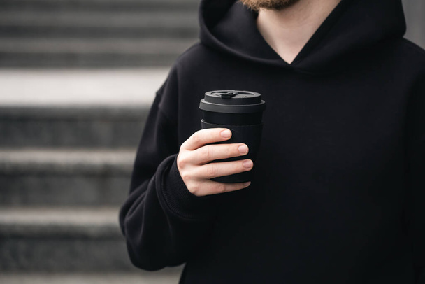 Reusable stylish bamboo black cup in the hands of a man, close-up, Eco friendly sustainable handy bamboo cup zero waste, no plastic concept. - Fotografie, Obrázek
