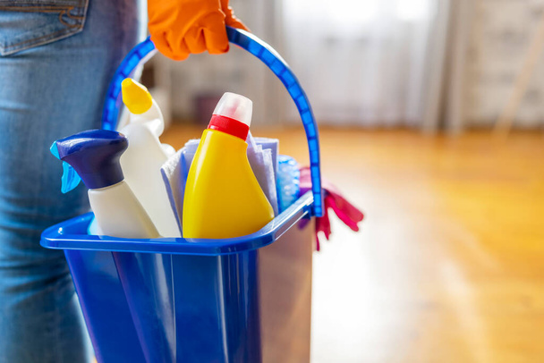 Mulher em luvas de borracha com balde de material de limpeza pronto para limpar seu apartamento. Dona de casa tem muitas tarefas domésticas, trabalho doméstico e serviço de limpeza profissional. Baixa profundidade de campo - Foto, Imagem
