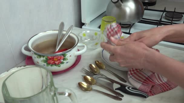 Женские руки с сухим полотенцем вытирать посуду на поверхности стола крупным планом. Домохозяйка очищает салфетку от мытья посуды. Бытовая уборка домашней утвари кухонные принадлежности. Горничная вытирает посуду дома. - Кадры, видео