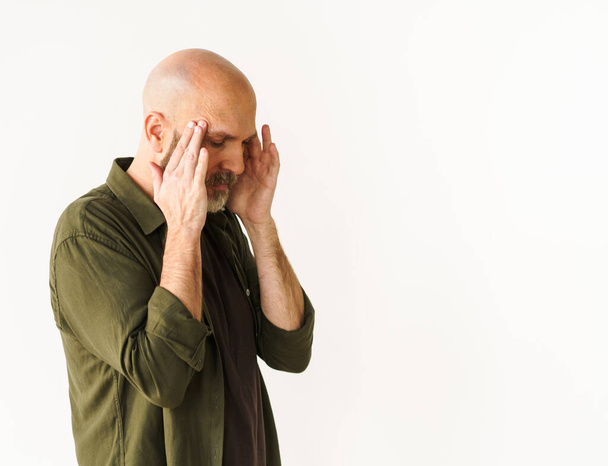 Mature man experiencing headache holds head with both hands. Concept of headache, conveying pain and discomfort that can accompany such experience. . High quality photo - 写真・画像