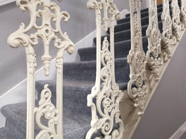 Εσωτερικό πλάνο της μοκέτας σκάλα με διακοσμητικά λευκά χυτοσίδηρο αγκάθια ή balustrades. Υψηλής ποιότητας φωτογραφία - Φωτογραφία, εικόνα