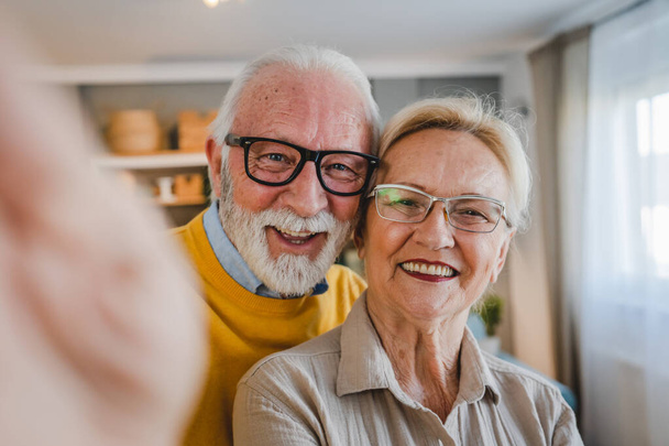 Portrait of senior husband and wife happy caucasian man and woman old couple at home taking selfie self portrait - Fotografie, Obrázek