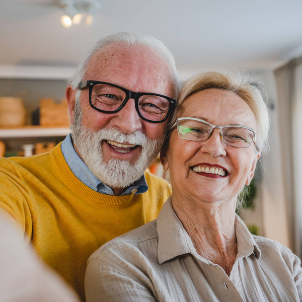 Retrato de marido y mujer mayores feliz caucásico hombre y mujer pareja de edad en casa tomando autorretrato selfie - Foto, imagen