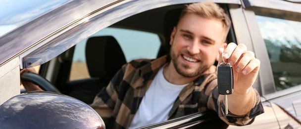 Ευτυχισμένος νεαρός άνδρας με κλειδί κάθεται στο νέο του αυτοκίνητο - Φωτογραφία, εικόνα