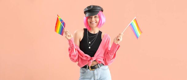 Όμορφη νεαρή γυναίκα με σημαίες ΛΟΑΤ σε μπεζ φόντο  - Φωτογραφία, εικόνα