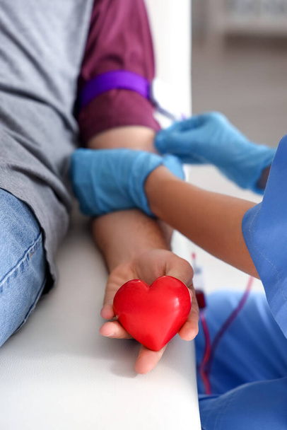 Joven con corazón donando sangre en la clínica, primer plano - Foto, Imagen