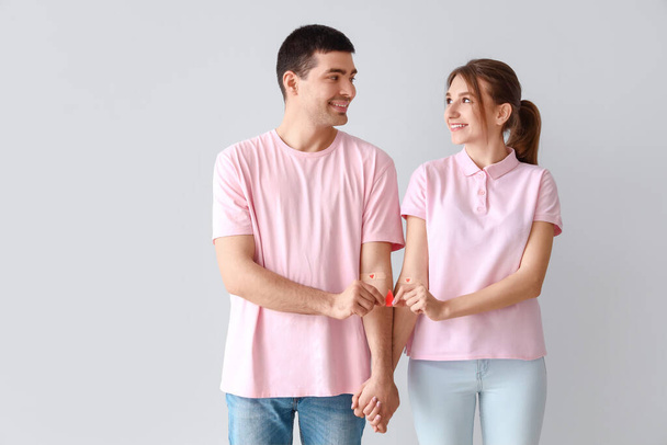 Young couple after donating blood with paper drop on light background - Φωτογραφία, εικόνα