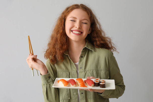 Young woman with sushi on light background - Foto, Imagen