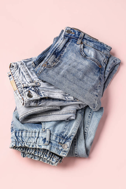 Different folded jeans on pink background - Foto, Imagem