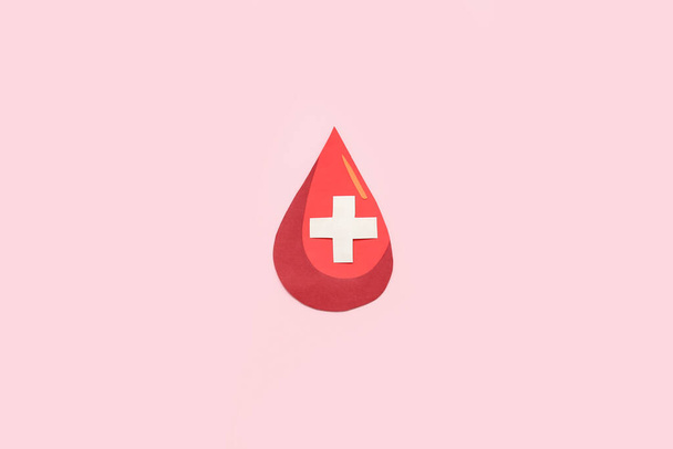 Papier goutte de sang avec croix sur fond rose. Journée mondiale des donateurs - Photo, image