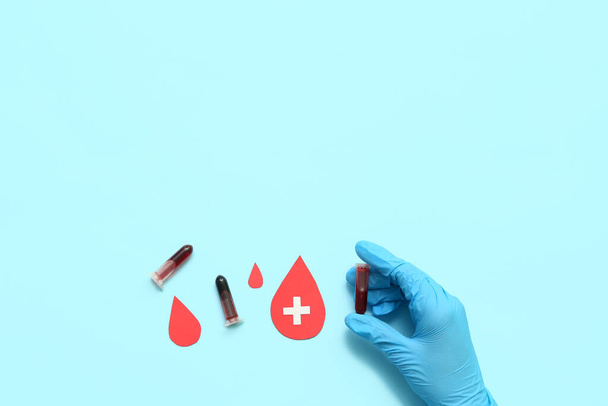 Γυναίκα γιατρός με δοκιμαστικούς σωλήνες και σταγόνες αίματος σε μπλε φόντο. Παγκόσμια Ημέρα Δωρητών - Φωτογραφία, εικόνα