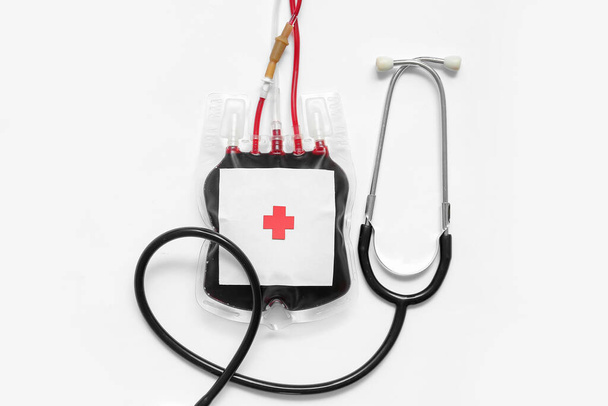 Pack sanguin avec stéthoscope sur fond blanc. Journée mondiale des donateurs - Photo, image