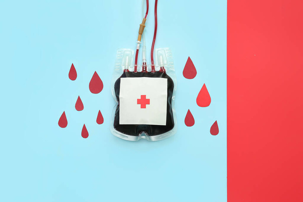 Envase de sangre con gotas de papel sobre fondo de color. Día Mundial del Donante - Foto, imagen