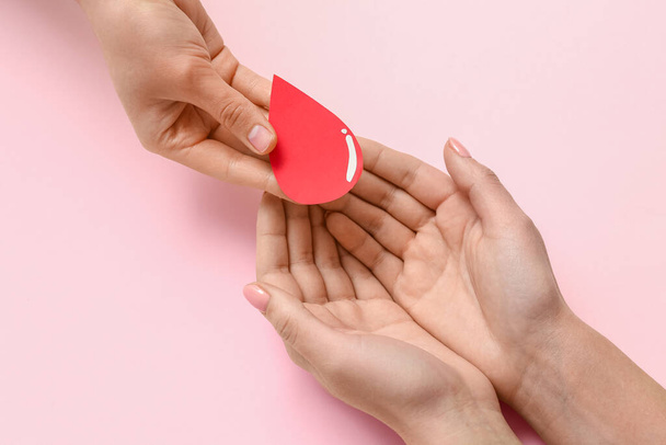 Women with paper blood drop on pink background. World Donor Day - Photo, Image