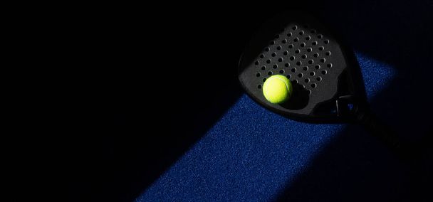 Raquete de tênis de remo profissional preto e bola com iluminação natural no fundo azul. Horizontal esporte tema cartaz, cartões de saudação, cabeçalhos, site e app - Foto, Imagem