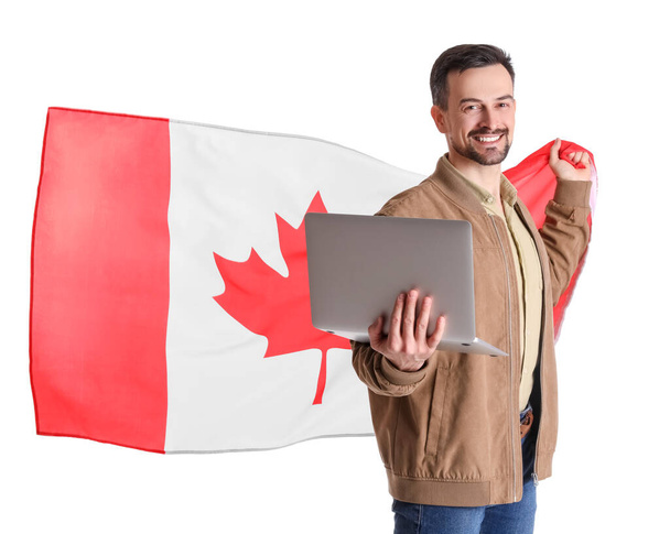 Handsome man with flag of Canada and laptop on white background - Фото, изображение