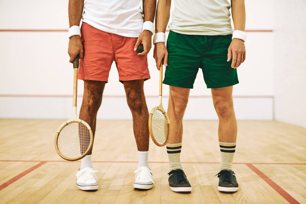 Squash oynamak için uygun giyinmelisin. İki adam raketlerini squash sahasında tutuyor. - Fotoğraf, Görsel