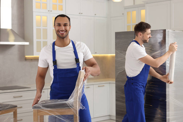 Male movers with chairs and refrigerator in new house - Photo, Image