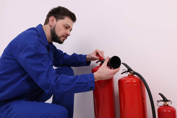 Man in uniform controleert brandblussers binnen - Foto, afbeelding
