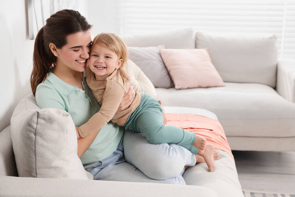 Mother with her cute little daughter on sofa at home, space for text - Φωτογραφία, εικόνα