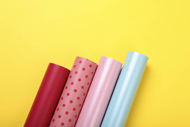 Rolls of colorful wrapping papers on yellow background, flat lay. Space for text - Valokuva, kuva