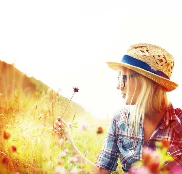 自由、健康と屋外の新鮮な空気のためのフィールドに花を持つレンズフレア、田舎やヒップスター女性。自然の牧草地で自然、夏と女性の人がリラックスし、穏やかな朝の平和のために. - 写真・画像