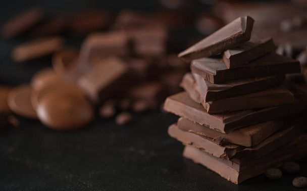 Closeup shot, of dark chocolate chunks on black background. Dessert food background. - Fotó, kép