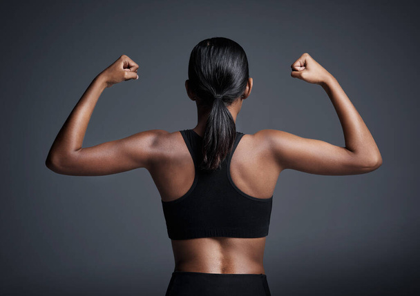 Sports, exercise and woman flexing back in studio isolated on a black background. Strong flex, muscle and female athlete with bicep, arm strength or bodybuilder training, fitness and healthy workout - Fotó, kép