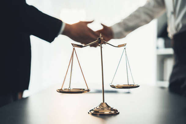 Focus gavel and justice scale on blur background of lawyer colleagues handshake after successful legal deal for lawsuit to advocate resolves dispute in court ensuring trustworthy partner. Equilibrium - Foto, Imagen
