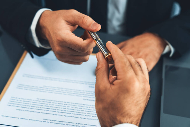 Two businesspeople sit across the desk as business deal is taking place. Corporate attorney giving a pen for client or partner to sign contract paper, sealing the deal with signature. Fervent - Photo, Image