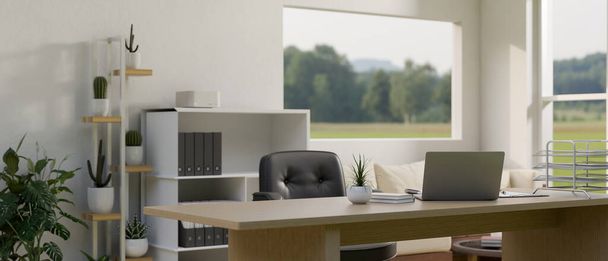 Interiérový design minimální bílé kancelářské místnosti s notebookem a kancelářskými potřebami na stole, kaktusovou policí, skříňkou na dokumenty a skleněným oknem s výhledem do přírody. 3D vykreslení, 3D ilustrace - Fotografie, Obrázek