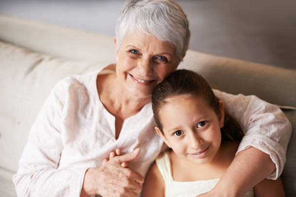 Πορτρέτο, χαμόγελο ή γιαγιά αγκαλιάζει ένα ευτυχισμένο κορίτσι με αγάπη στο οικογενειακό σπίτι στις διακοπές μαζί. Παιδί, αγκαλιά ή ηλικιωμένη γιαγιά χαλάρωση ή δέσιμο για να απολαύσετε ποιοτικό χρόνο στη συνταξιοδότηση. - Φωτογραφία, εικόνα