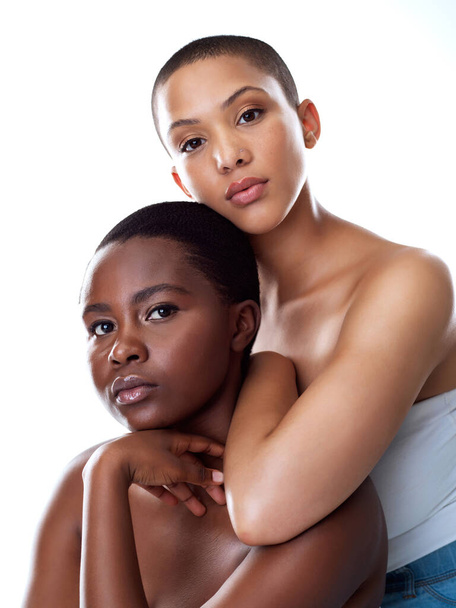 She will protect me from anything. Portrait of two beautiful young women holding each other while standing against a white background - Foto, Imagem