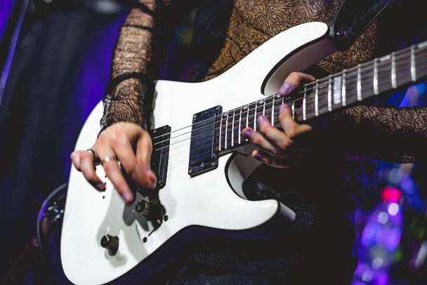 Электрическая симфония: рок-музыкант играет на поразительной белой электрогитаре на сцене - Фото, изображение