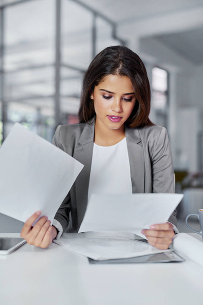 Getting business all in order. a young businesswoman looking through some paperwork in an office - Foto, afbeelding