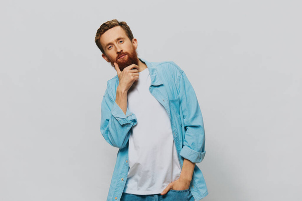 Ritratto maschile hipster sorriso su sfondo grigio in camicia blu e t-shirt bianca, ritratto di un uomo con la barba. Foto di alta qualità - Foto, immagini