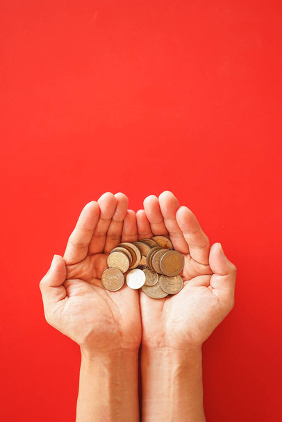 mão segurando moedas em um fundo vermelho - Foto, Imagem