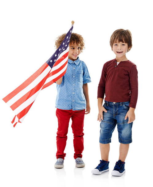 Празднование разнообразия. Студийный снимок двух милых мальчиков, держащих американский флаг вместе на белом фоне - Фото, изображение