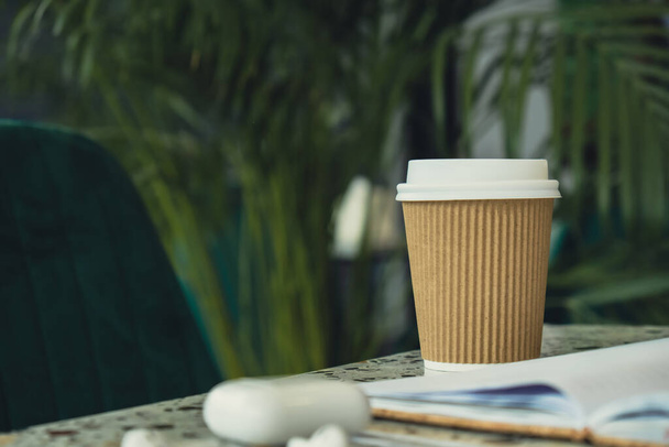 Emportez le café dans une tasse en papier de recyclage artisanal avec carnet en papier avec écouteurs sans fil. Maquette Pause café. Guérison audio, thérapie sonore rituels de bien-être, habitudes de santé mentale positives écoute - Photo, image