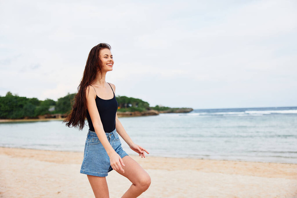 mujer joven costa viaje actividad playa relajarse correr largo atardecer verano estilo de vida sonrisa femenina hermoso cabello bronceado sonriente mar caminar ola ocio - Foto, imagen