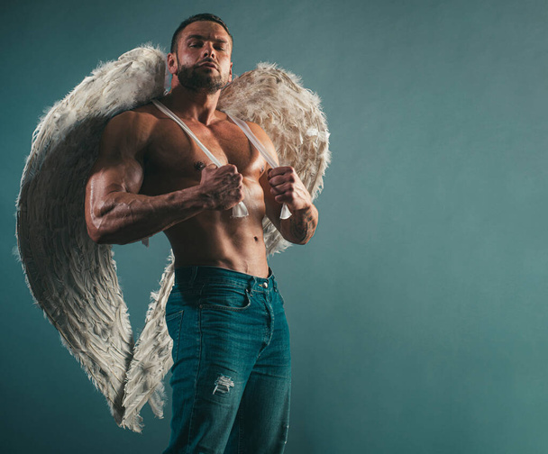 Young man with angels wings. Strong man showing his perfect naked body. Bare torso - Foto, afbeelding