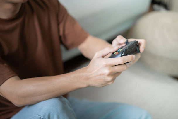 Νεαρός Ασίας άνθρωπος gamer ελεγκτή βίντεο κονσόλα παίζοντας κρατώντας χόμπι παιχνιδιάρικο σε απευθείας σύνδεση βίντεο παιχνίδι απόλαυση eSport Cyber Games Internet - Φωτογραφία, εικόνα