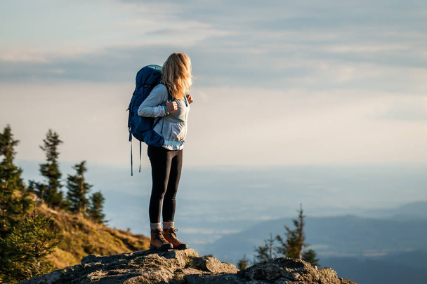 Nainen vaeltamassa vuorilla. Matkailija reppu seisoo vuoren huipulla ja etsivät kauniita maisemia. Luonnon nautinto - Valokuva, kuva