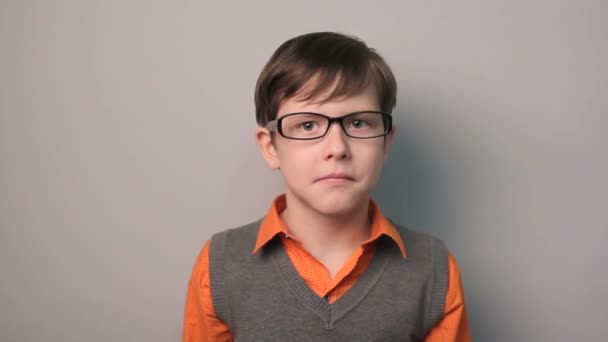 teenager boy swears row waving his arms opened his mouth in  glasses on gray background - Footage, Video
