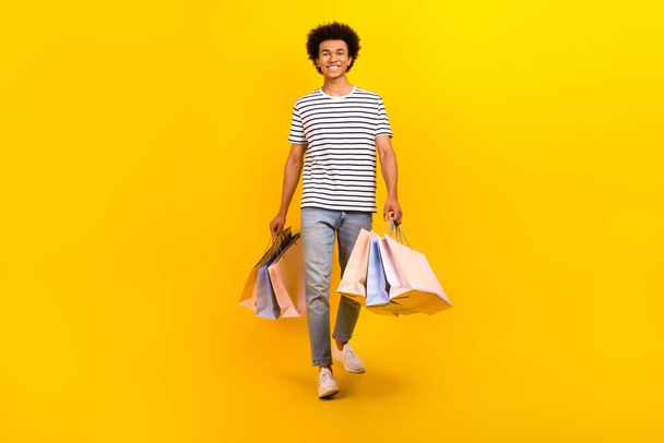 Full length cadre of young shopaholic man black friday advert promo walks hold packages outlet store isolated on yellow color background. - Foto, immagini