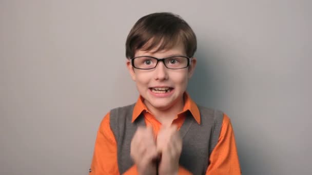 boy hands to his mouth fright shock glasses ten years on gray background - Footage, Video
