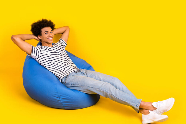 Full body photo of young student chilling dormitory hands head take nap after lectures sitting pouf isolated on yellow color background. - Foto, Bild