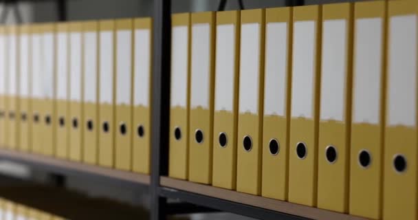 Struttura organizzata di raccoglitori ad anello gialli in piedi su scaffali di rack in ufficio moderno. Cartelle con materiale d'archivio e informazioni contabili - Filmati, video