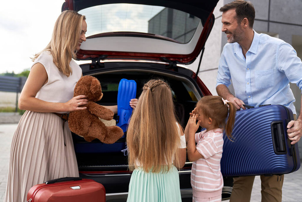 Famiglia caucasica di quattro bagagli da imballaggio nel bagagliaio dell'auto prima delle vacanze - Foto, immagini