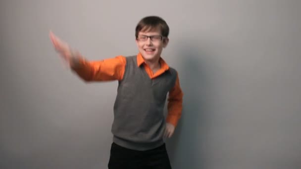Teenie-Junge tanzt lustig und fuchtelt mit den Armen in Brille vor grauem Hintergrund - Filmmaterial, Video